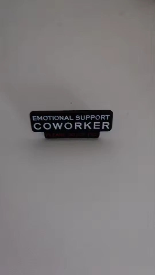 Emotional Support Coworker pin held in hand